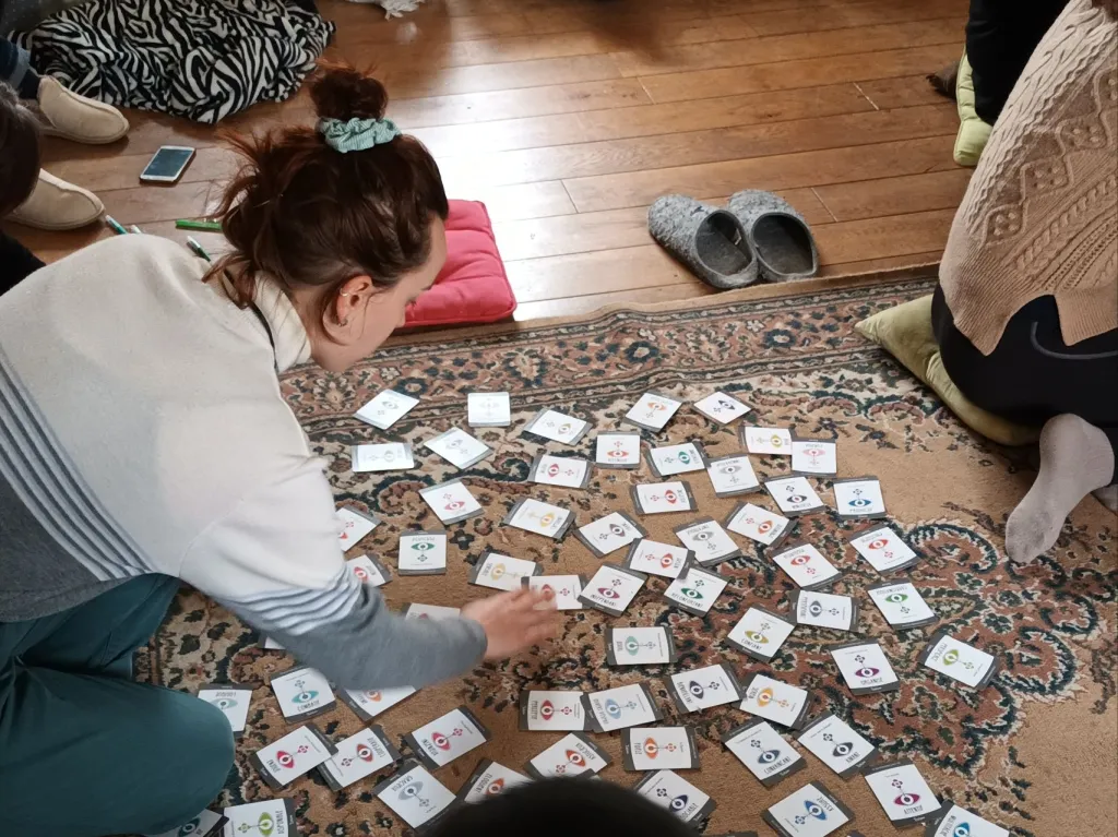 Participant utilisant des cartes de facilitation étalées sur un tapis, lors d'un atelier collaboratif en intérieur.